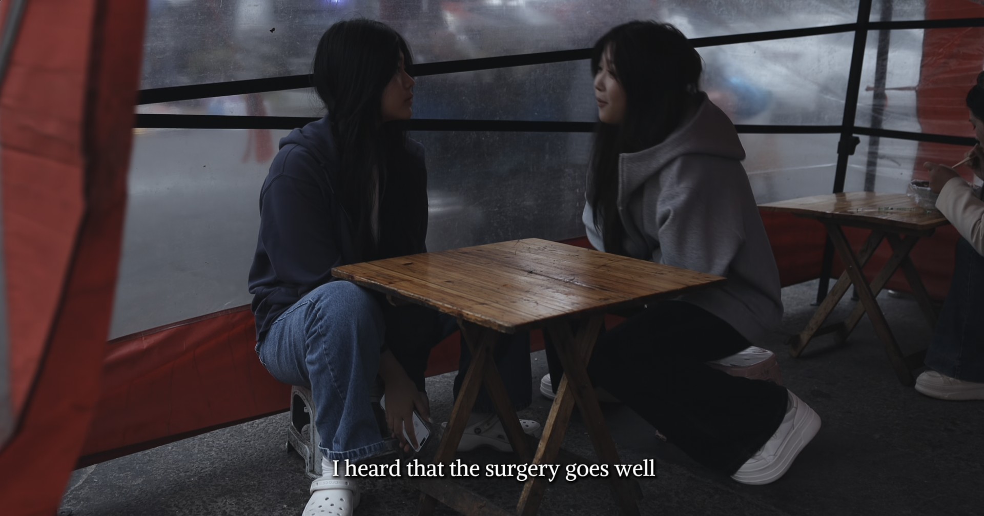 Two girls talking at a table with the original subtitles