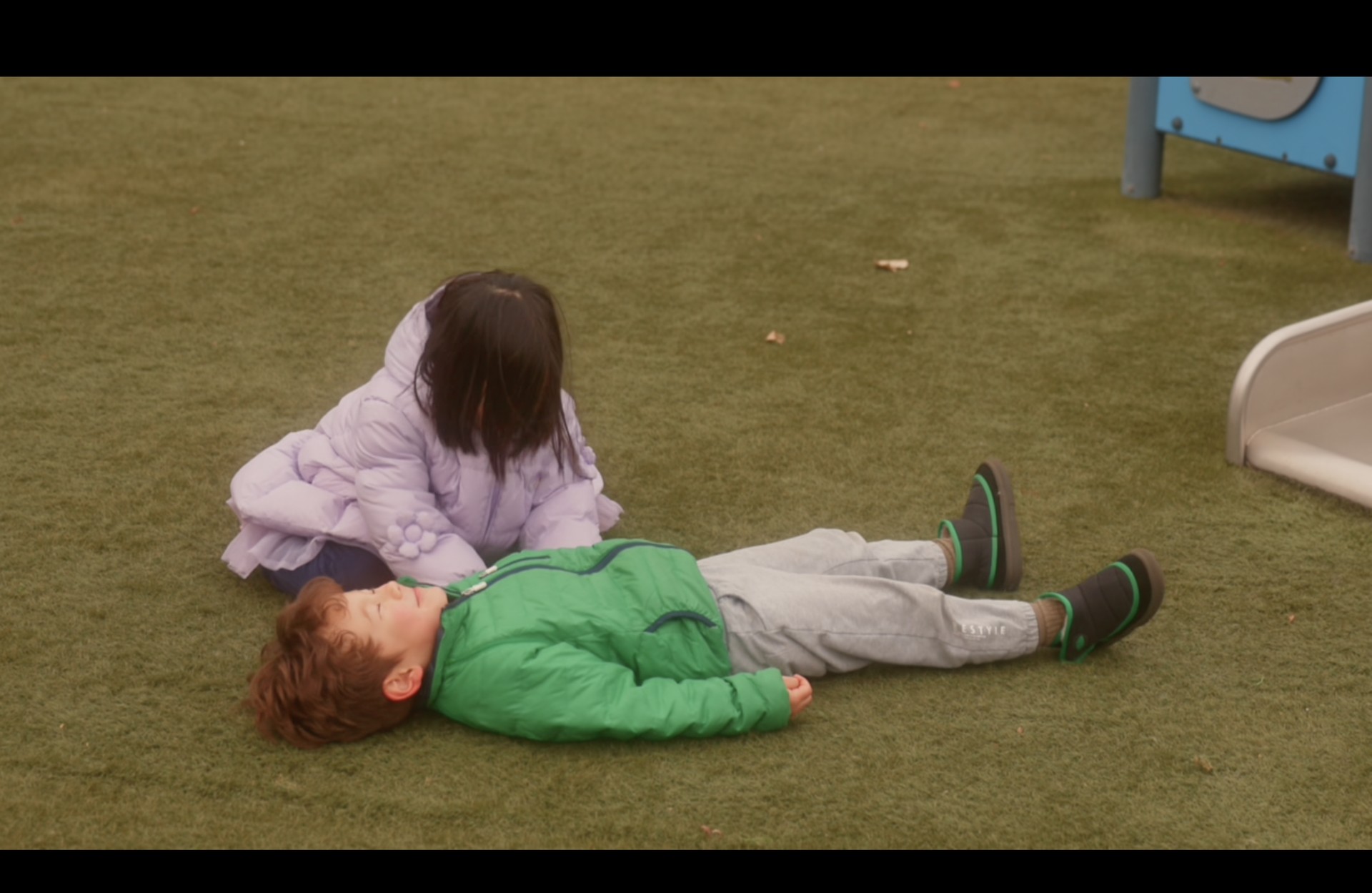 Girl beside a boy lying on the grass, with the original player frame